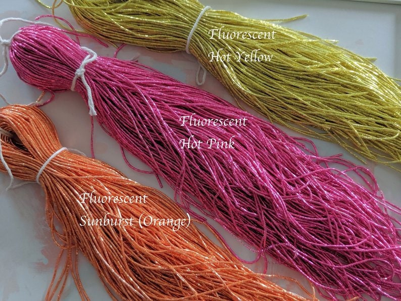 May include: Three spools of fluorescent thread in hot pink, hot yellow, and sunburst orange.