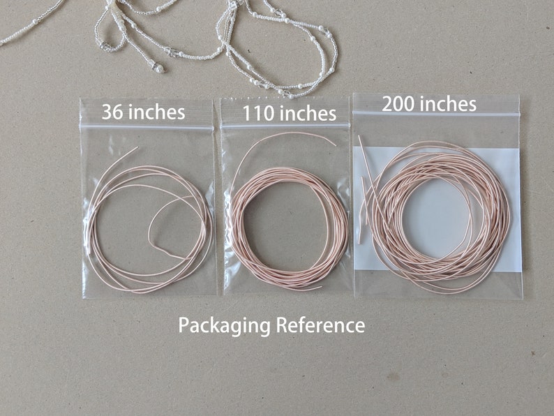 May include: Three clear plastic bags with pink string spools inside. The bags are labeled with the lengths of the string: 36 inches, 110 inches, and 200 inches. The text "Packaging Reference" is printed below the bags.