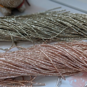 May include: Two spools of metallic thread, one silver and one rose gold. The thread is very fine and has a sparkly finish.