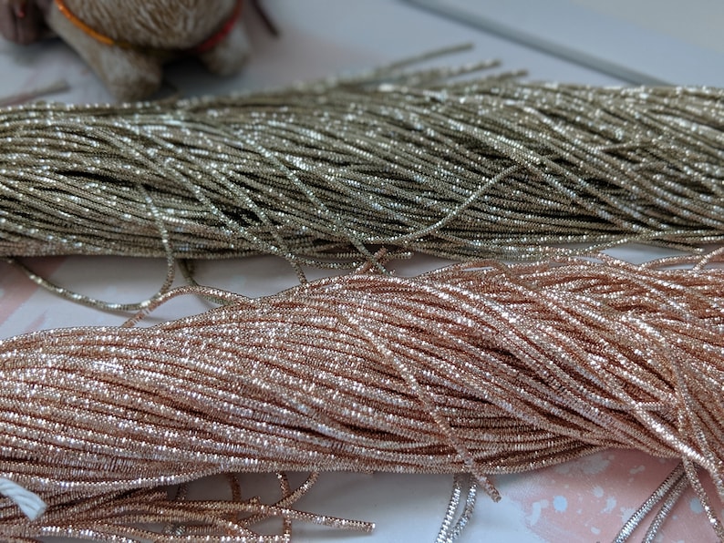 May include: Two spools of metallic thread, one silver and one rose gold. The thread is very fine and has a sparkly finish.