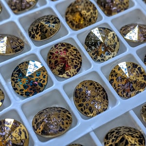 May include: A close-up of a tray of round, faceted rhinestones with a leopard print pattern. The rhinestones are in various colors, including gold, red, and blue.