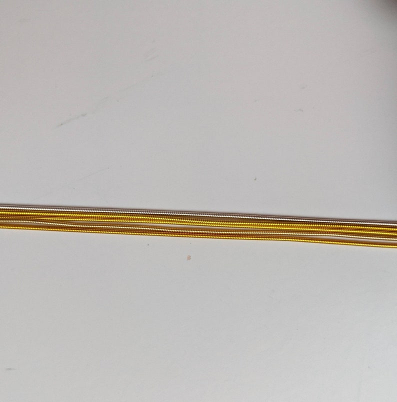 May include: Close-up of four strands of gold, silver, and copper wire.