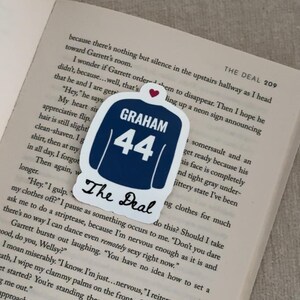 May include: A navy blue sticker in the shape of a jersey with the name "GRAHAM" and the number "44" in white. The text "The Deal" is below the jersey. A small red heart is at the top.