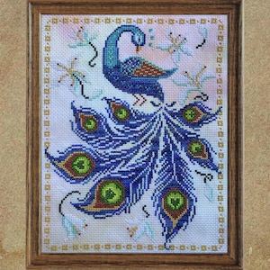 Pode incluir: Obra de arte em ponto cruz emoldurada com um pavão com corpo e penas da cauda azuis. A cauda do pavão exibe padrões detalhados com detalhes verdes e amarelos. O fundo é rosa claro com detalhes florais e musicais.