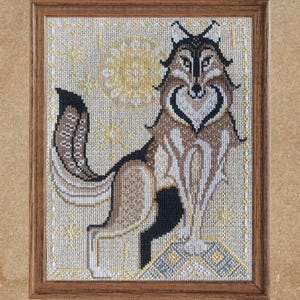Puede incluir: Arte de punto de cruz enmarcado que representa un lobo estilizado con un pecho en forma de corazón. El lobo está representado en tonos marrones, negros y blancos, sobre un fondo crema con un sol amarillo y un borde decorativo. La obra está enmarcada en madera.
