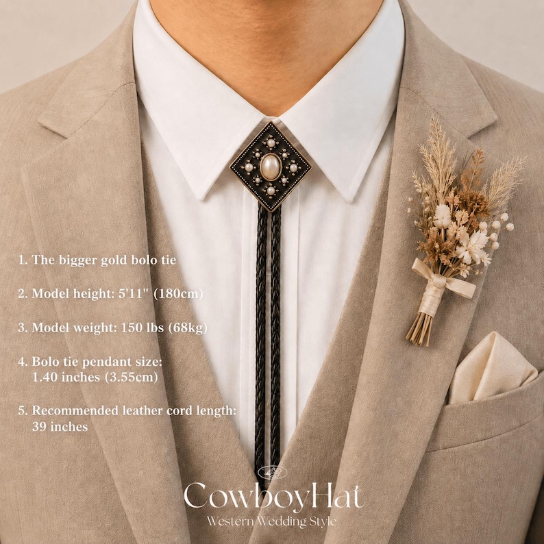 May include: A gold bolo tie with a diamond-shaped pendant featuring a central pearl and surrounding embellishments. The black leather cord hangs over a white collared shirt, paired with a beige suit. A small floral boutonniere and the text "Cowboy Hat" are also visible.