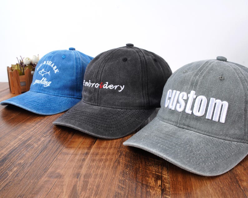 Pu&ograve; includere: Tre cappellini da baseball in blu, nero e grigio. Il cappellino blu presenta la scritta bianca Shark Yachting. Il cappellino nero ha la scritta bianca embroidery con una o rossa. Il cappellino grigio presenta la scritta bianca custom in stampatello.