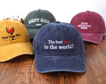 May include: Four different baseball caps with embroidered text. One cap is yellow with a wine glass and the text "Your Logo Here". One cap is green with the text "BEST DAD". One cap is red with the text "YOUR TEXT/LOGO HERE". One cap is blue with the text "The best dad in the world!"
