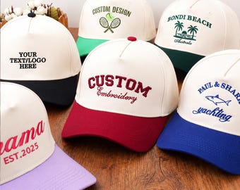 May include: A collection of white baseball caps with colored brims. Each cap features custom text or logos, including "CUSTOM DESIGN," "BONDI BEACH," and "CUSTOM Embroidery." The brims are in various colors, such as black, green, red, and blue.