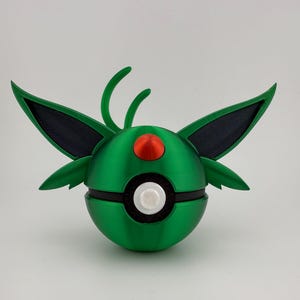 May include: A green and black spherical object with wing-like structures and a red and white circular design. The object has a rounded shape with a segmented design, and is likely a decorative item or toy.