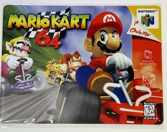 Può includere: Un cartello in metallo con il videogioco Mario Kart 64. L'artwork mostra Mario, Wario e Donkey Kong nei loro kart che corrono su una pista. Sono visibili anche il logo Nintendo 64 e la scritta "Only For".
