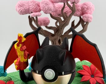 May include: A black and gold decorative figure with red wings and a flame. The figure is set on a green surface with red flowers and a pink tree in the background. The figure has a round shape with a white button.