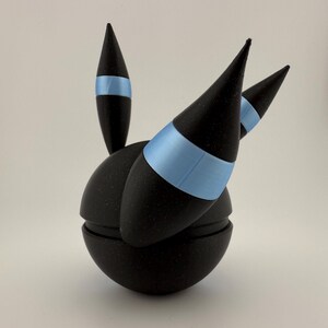May include: A black, spherical object with three conical spikes and a single, smaller spike. Each spike has a light blue band. The object is split into two halves, with a textured surface.