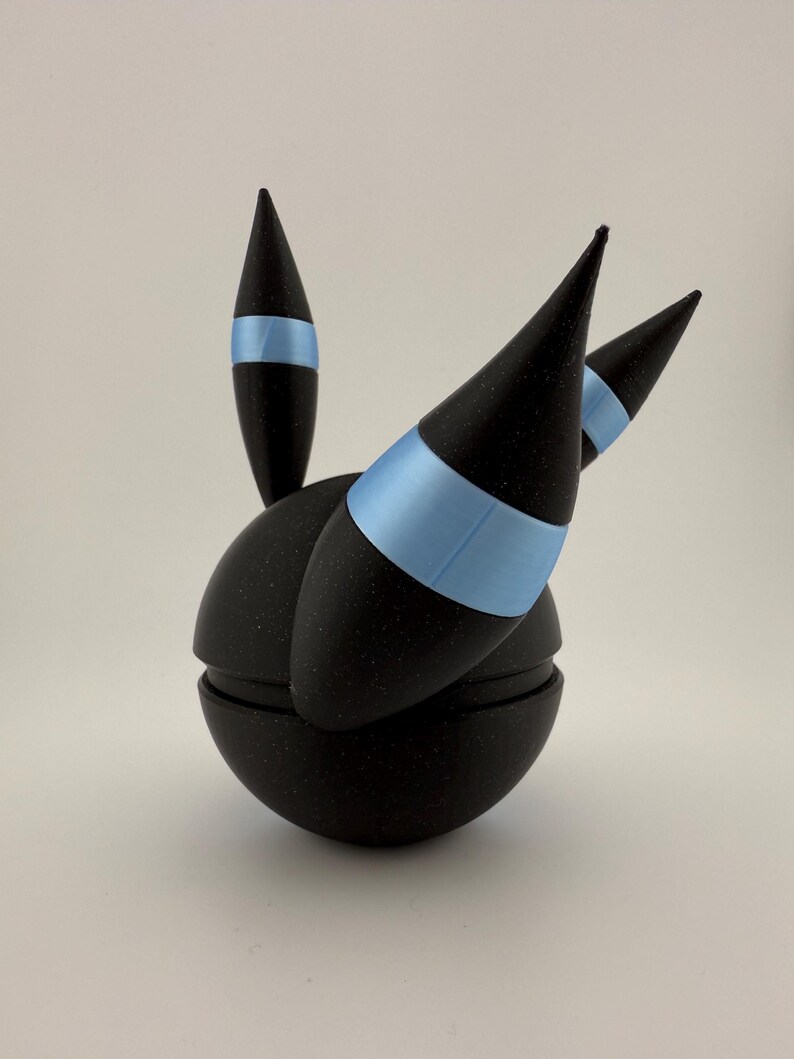 May include: A black, spherical object with three conical spikes and a single, smaller spike. Each spike has a light blue band. The object is split into two halves, with a textured surface.