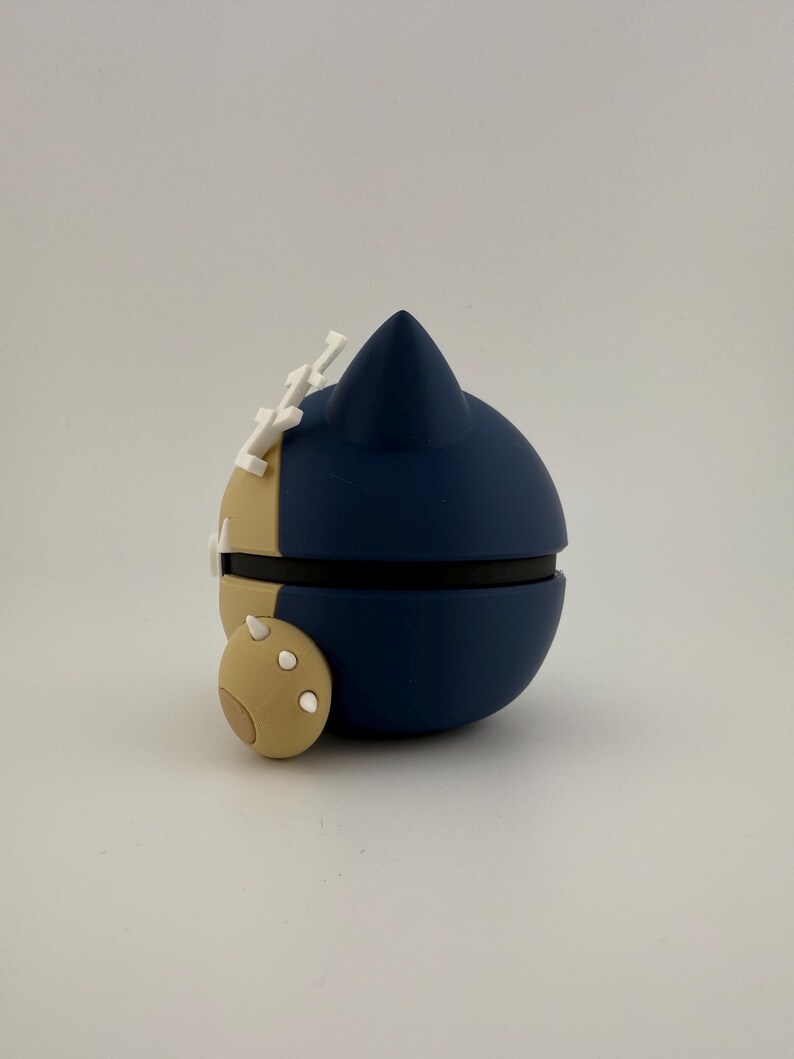 May include: A navy blue and tan spherical object with white accents. The object has a rounded shape with a pointed top and a small, circular appendage. The object is likely a decorative item or a collectible.