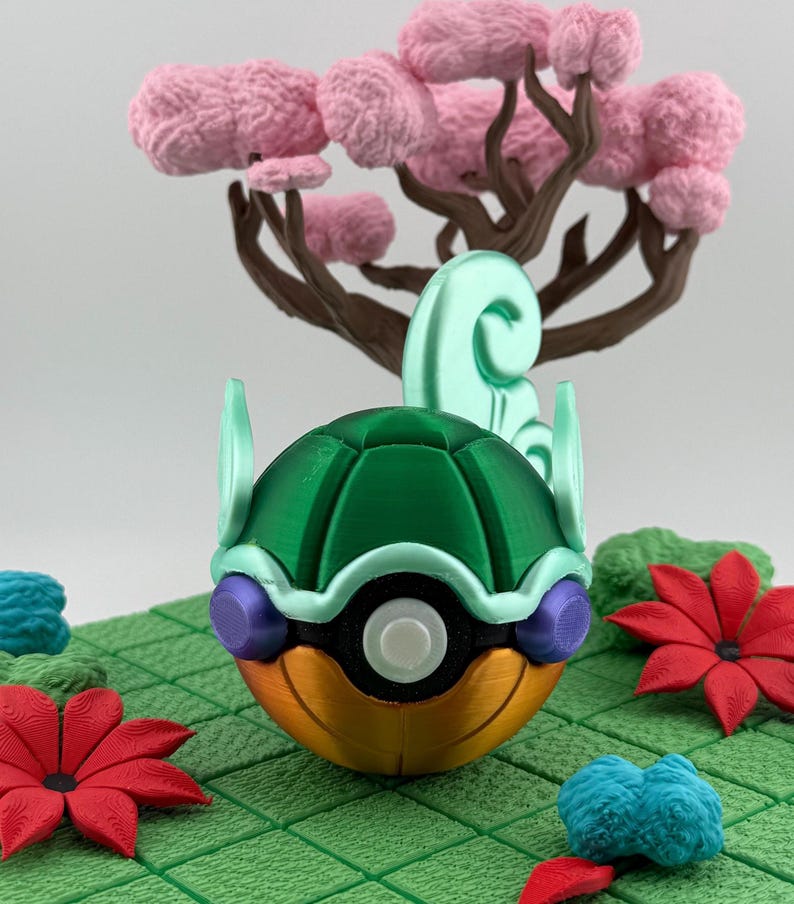Pode incluir: Uma esfera decorativa multicolorida impressa em 3D, com uma parte superior verde, uma parte inferior laranja e um centro branco. A esfera &eacute; cercada por flores vermelhas, folhagem azul e verde e uma &aacute;rvore rosa com galhos marrons. A cena est&aacute; em uma grade verde.