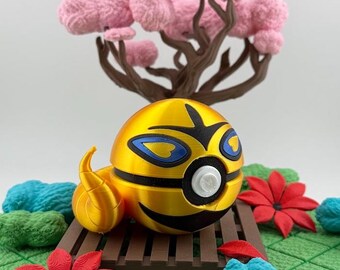 Op de afbeelding: Een geel en zwart 3D-geprint personage met blauwe accenten en een wit knoopoog, rustend op een bruin platform. De scène bevat rode bloemen, blauwe en groene texturele elementen en een roze boom.