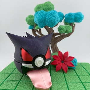May include: A purple and black figure with red accents and a pink tongue, resembling a cartoon character, sits on a green platform. A red flower and a tree with blue and green foliage are in the background.