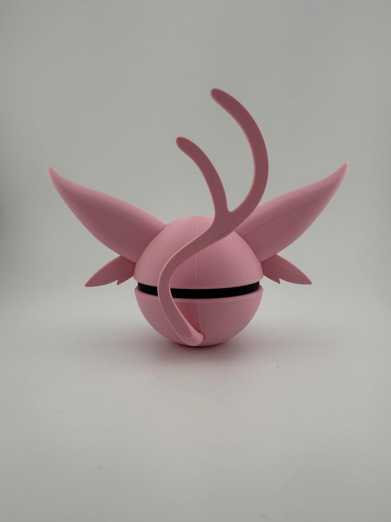 May include: A pink, spherical sculpture with wing-like projections and curved, antler-like elements. A black band encircles the sphere. The design is symmetrical and appears to be 3D-printed.