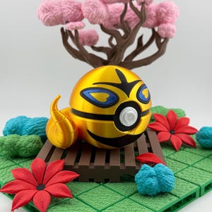 May include: A golden, spherical character with blue and black accents, resting on a brown platform. The character has a flame-like tail. The scene includes red and blue floral elements, green foliage, and a pink tree.
