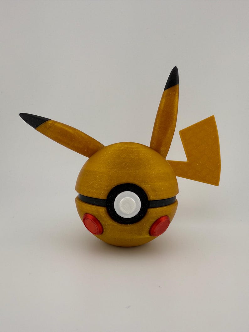 May include: A golden-yellow, spherical object with black and red accents, resembling a cartoon character. The object has two pointed ears with black tips, a lightning bolt tail, and a black stripe around the middle. Two red circles are on the bottom.