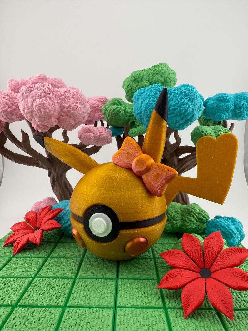 May include: A golden-yellow, spherical character with a black and white eye, orange bow, and pointed ears. The character is surrounded by a green, grid-like surface, red flowers, and colorful, textured trees with pink, green, and blue foliage.