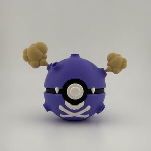May include: A purple and white cartoon-style Poke Ball with tan smoke-like accents. The ball has a black band and a white skull and crossbones design. The design is reminiscent of a cartoon character.