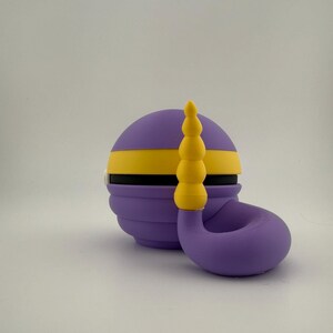 May include: A purple and yellow decorative object with a curved, horn-like shape. The object has a spherical base with a yellow stripe and a series of stacked yellow spheres on top. The design is whimsical and colorful.