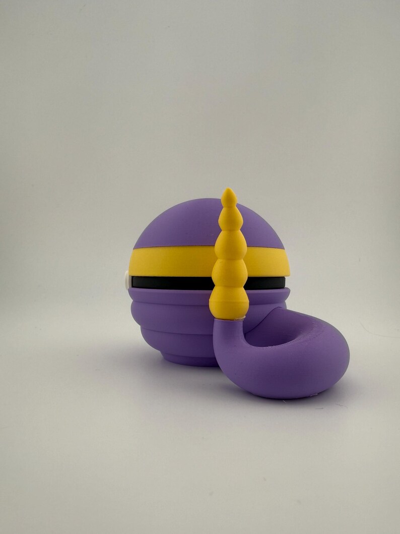 May include: A purple and yellow decorative object with a curved, horn-like shape. The object has a spherical base with a yellow stripe and a series of stacked yellow spheres on top. The design is whimsical and colorful.