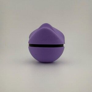 May include: A spherical, purple object with a black band around the middle. The top portion has a textured, ridged design. The object is set against a plain, white background. The overall shape is reminiscent of a rounded, stylized form.