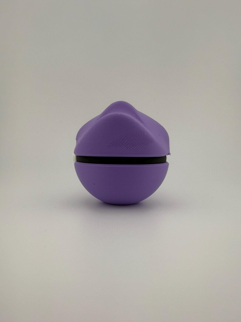 May include: A spherical, purple object with a black band around the middle. The top portion has a textured, ridged design. The object is set against a plain, white background. The overall shape is reminiscent of a rounded, stylized form.