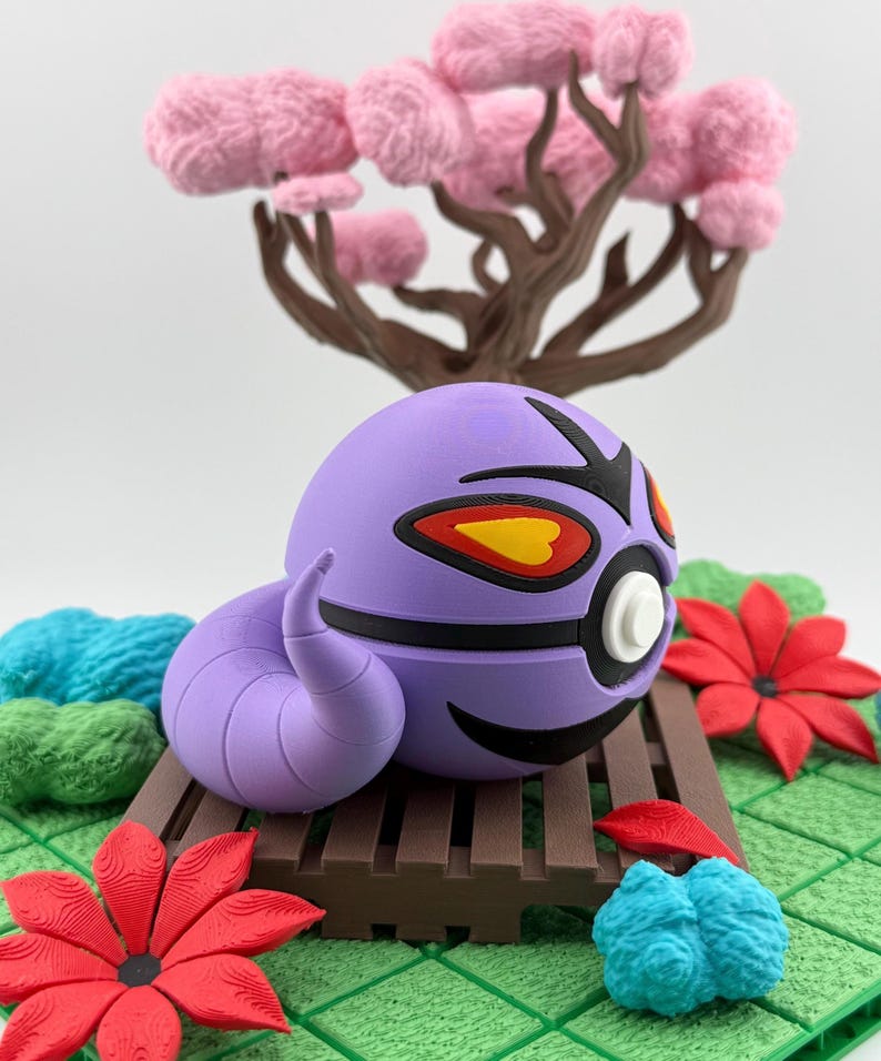 May include: A purple, spherical creature with black and yellow accents, a curved tail, and a white eye, resting on a brown wooden platform. The scene includes a pink tree and red and blue floral elements, set against a green, textured background.