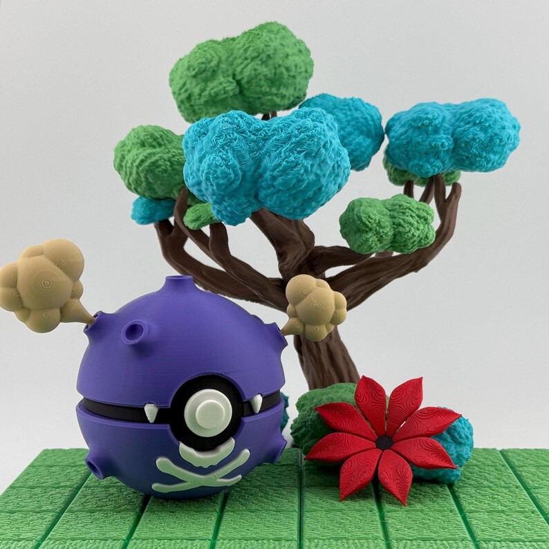 May include: A purple, spherical character with a skull and crossbones design, white eyes, and small teeth. It is positioned in front of a brown tree with green and blue textured foliage. A red flower and beige cloud-like shapes are also present.