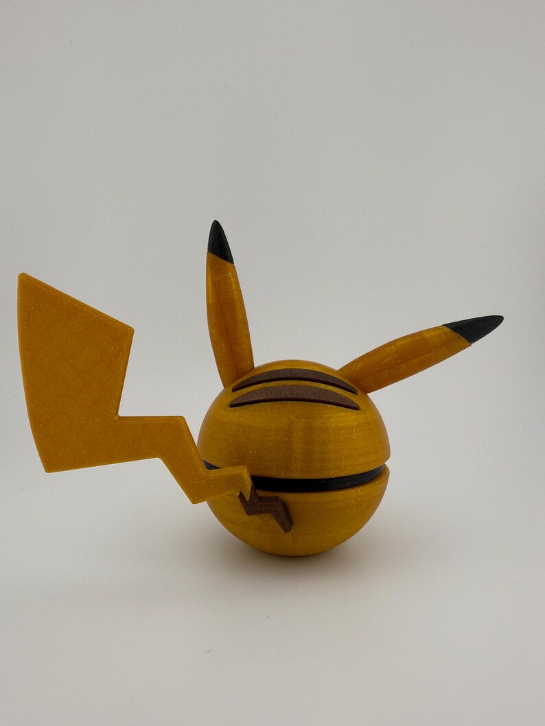 May include: A 3D-printed Pikachu figure in yellow and brown. The figure has a spherical body with a lightning bolt tail and pointed ears with black tips. The figure is a collectible item.