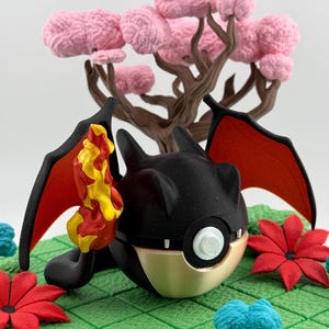 May include: A black and gold fantasy creature with red wings and a yellow and orange flame. The creature is set on a green surface with red flowers and a pink tree in the background. The scene is a whimsical, fantasy-themed design.