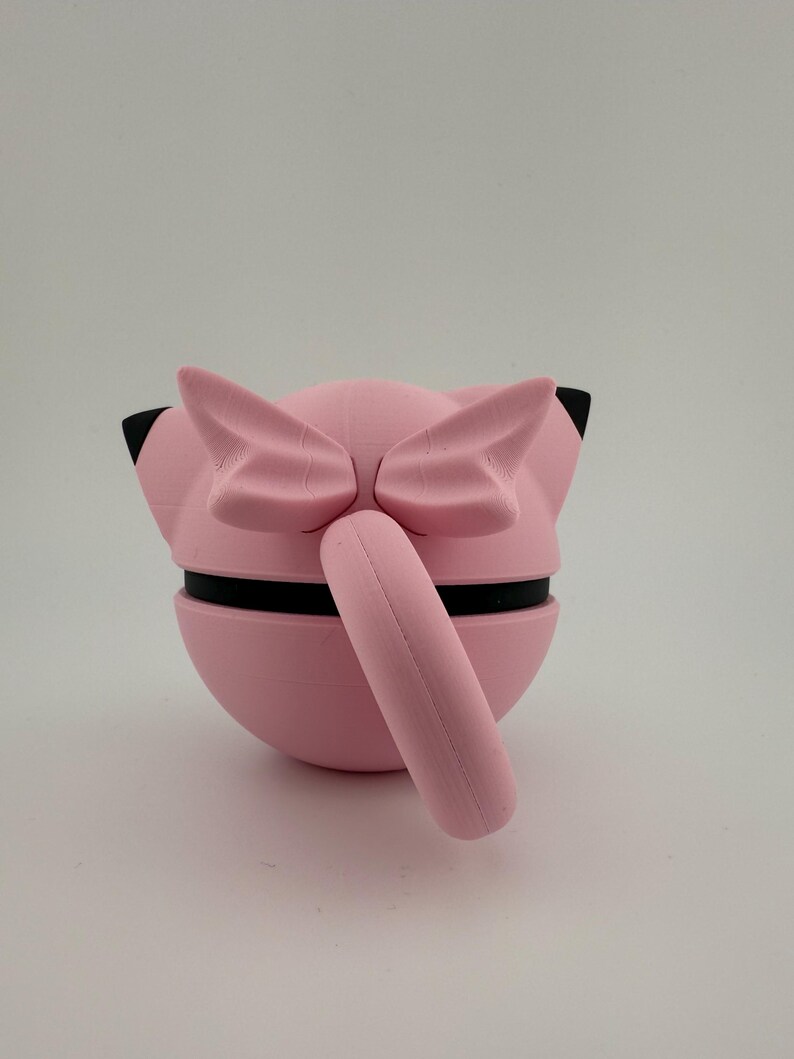 K&ouml;nnte beinhalten: Eine rosa 3D-gedruckte Skulptur einer Zeichentrickfigur mit gro&szlig;en Ohren und einem Schwanz. Die Skulptur hat schwarze Akzente und ist vor einem wei&szlig;en Hintergrund platziert. Der K&ouml;rper der Figur ist kugelf&ouml;rmig und der Schwanz zylindrisch.