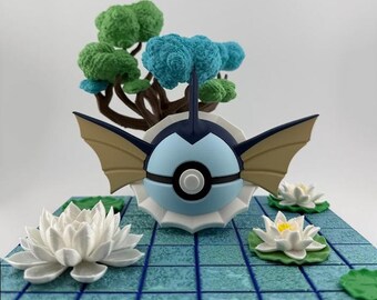 Op de afbeelding: Gedetailleerd beeldje van een blauw-wit wezen met bruine vleugels, geplaatst op een blauwe betegelde basis met witte lotusbloemen en een miniatuurboom met groen en blauw gebladerte. Het beeldje heeft een zwarte streep.