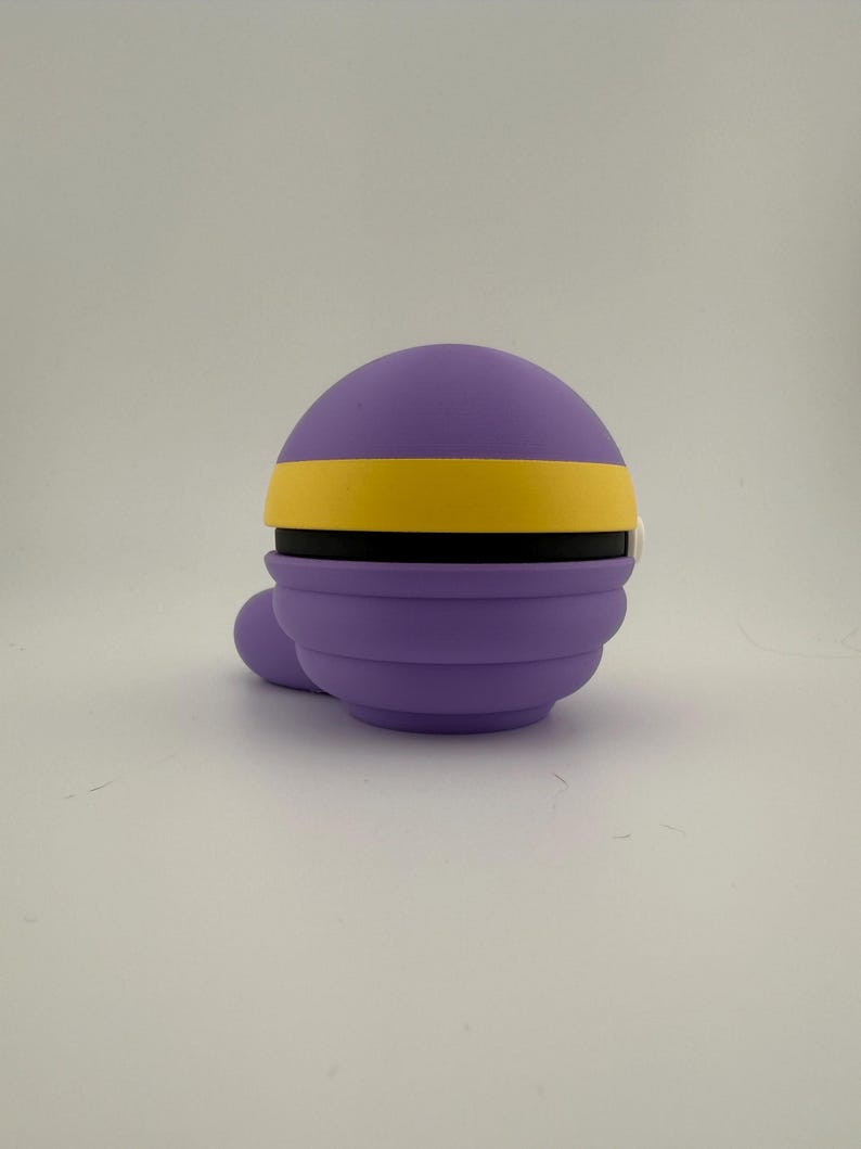 May include: A purple, spherical object with a yellow band and a small, rounded protrusion. The object has a layered design and appears to be made of a soft material. The background is plain white.