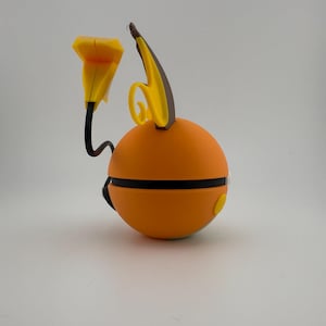 May include: An orange, spherical object with black and yellow accents. The object has a black band around the middle and a yellow button on the side. A yellow, flower-like shape and a curved, yellow and brown shape extend from the top.