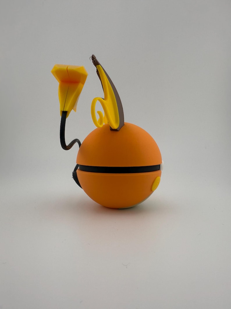 May include: An orange, spherical object with black and yellow accents. The object has a black band around the middle and a yellow button on the side. A yellow, flower-like shape and a curved, yellow and brown shape extend from the top.