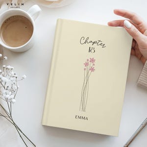 May include: A cream-colored book with the words "Chapter 18" in script and a floral design. The name "Emma" is printed below the design. A cup of coffee and flowers are in the background.