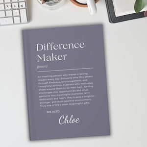Może przedstawiać: Szary notatnik z białymi słowami "Difference Maker". Definicja "Difference Maker" jest wydrukowana pod tytułem. Nazwisko "Chloe" jest wydrukowane na dole notatnika.