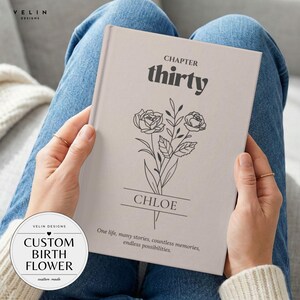 May include: A light beige hardback book featuring black text and a floral line drawing. The cover displays the words "CHAPTER thirty", "CHLOE", and "One life, many stories, countless memories, endless possibilities." The book is held against blue jeans.
