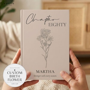 May include: A light beige hardback book featuring a dark grey line art illustration of a wildflower bouquet. The text reads Chapter EIGHTY, MARTHA, and Stronger with every season. A circular logo in the corner displays CUSTOM BIRTH FLOWER.