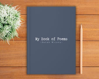 Può includere: Un libro blu scuro intitolato "My Book of Poems" di Sarah Wilson. Una matita di legno e una piccola pianta verde sono accanto al libro su una superficie di legno. La copertina del libro è di colore pieno e opaco.