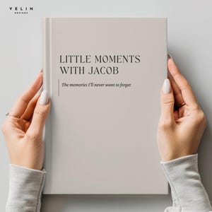 Peut inclure: Un livre à couverture rigide beige clair avec le texte "LITTLE MOMENTS WITH JACOB" et "The memories I'll never want to forget" imprimé en noir sur la couverture. Le livre présente un accent de ligne verticale et la marque "VELIN DESIGNS".