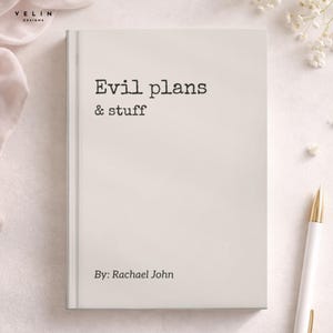 May include: A rectangular notebook with a light beige cover featuring the black printed text "Evil plans & stuff" and "By: Rachael John" in a typewriter-style font. The notebook is positioned vertically with a white pen placed to the right side.