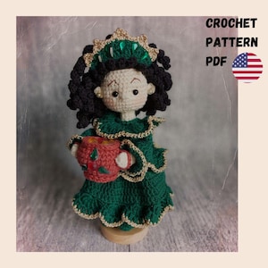 May include: A handmade crochet doll wearing a green dress with gold trim and a matching crown. The doll has black curly hair and is holding a red cup. The image includes the text "CROCHET PATTERN PDF" and an American flag.