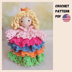 May include: A handcrafted crochet princess doll with blonde curly hair and a peach crown. The doll wears a layered dress in pink, fuchsia, blue, orange, and green. The text "CROCHET PATTERN PDF" is visible. The image also includes the American flag.