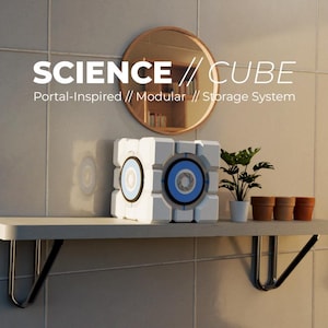 Puede incluir: Un sistema de almacenamiento en forma de cubo blanco y azul con el texto "SCIENCE // CUBE" y "Portal-Inspired // Modular // Storage System". El cubo está sobre una estantería con una pequeña planta y macetas. Un espejo redondo cuelga encima.